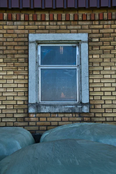 Ujęcie Okna Ceglanej Ścianie Duże Bele Kiszonki Owinięte Plastikiem Przodu — Zdjęcie stockowe