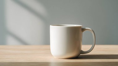 Temiz beyaz bir kupa, ahşap bir yüzeyde, yumuşak, rahatlatıcı gölgeler ve atmosfer yaratan, doğal güneş ışığıyla aydınlatılmış, zarif bir şekilde oturmaktadır..
