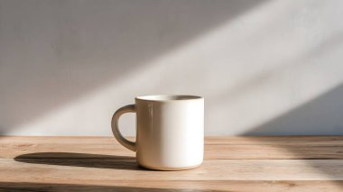 Temiz beyaz bir kupa, ahşap bir yüzeyde, yumuşak, rahatlatıcı gölgeler ve atmosfer yaratan, doğal güneş ışığıyla aydınlatılmış, zarif bir şekilde oturmaktadır..