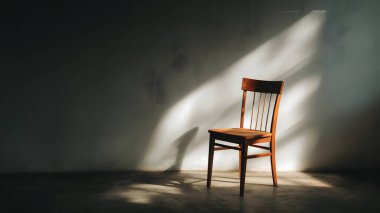 Zarif ahşap bir sandalye, doğal ışıkla aydınlatılmış bir odada tek başına durur. Sanatsal ve rahatlatıcı bir gölge kontrastı yaratır..