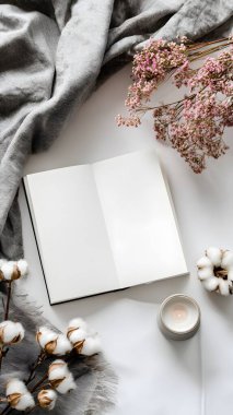 Yumuşak bir sabah ışığı, narin kurumuş çiçeklerle çevrili boş bir kitabı aydınlatır ve güne huzurlu bir başlangıç yapar..