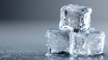 Islak, siyah ve dramatik bir yüzeye su damlacıklarıyla dolu birkaç soğuk ve ıslak buz küpünün yakın çekimi..