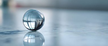 Temiz bir cam top, gri minimalist desenli arka planda güzel bir ışık kırılması ve keskin bir yansıma yaratır..