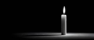 Yalnız beyaz bir mum, koyu bir arka planda parlar, dokulu bir yüzeye uzun ve dramatik bir gölge bırakır..