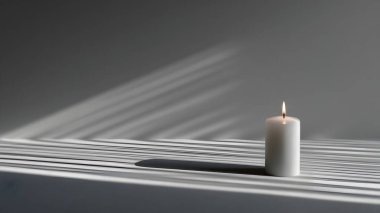 Sıcak, parıldayan bir mum desenli bir yüzeye oturur. Yakınlardaki bir pencereden geçen güneş ışığıyla güzelce aydınlatılır..