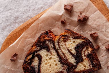 Parşömen kâğıdında çikolata kıvrımlı mermer pasta, kırsal tatlı, ahşap arka plan.