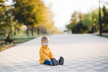 3-4 yaşlarında sarı örgü süveter giyen mutlu bir kız çocuğu parkta oynuyor. Sonbahar sezonu. Çocukluk. Kameraya bakıyorum.. 