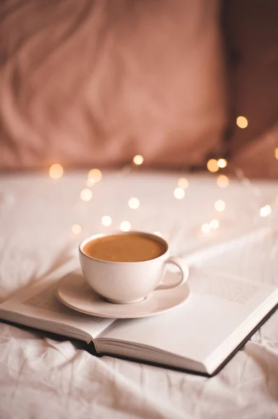 Mug Fresh Tasty Coffee Open Paper Book Bed Christmas Lights — Stock Photo, Image