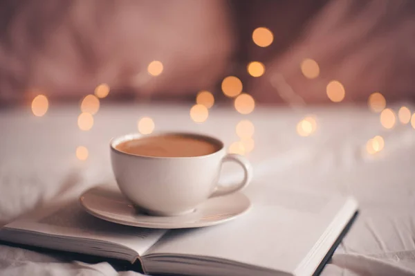 Cup Coffee Stayin Open Pepaer Book Glowing Christmas Lights Close — Stock Photo, Image