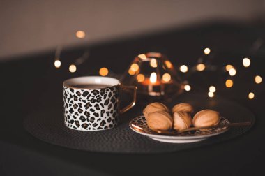 Taze çay tabağında lezzetli pastalar yanan mumlar ve Noel ışıklarıyla. Kış tatili. Sıcak ev atmosferi. Kutlama. Günaydın.. 