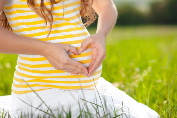 Pregnant woman with heart shaped sign — Stock Photo, Image