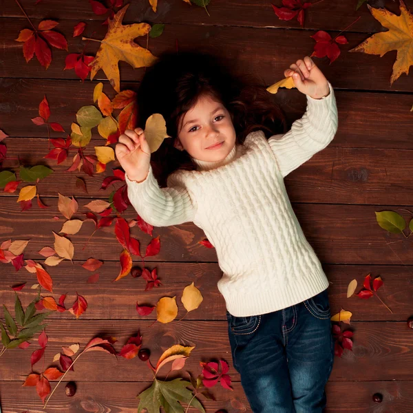 Pequeña linda chica con hojas caídas — Foto de Stock