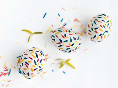 Üç Paskalya yumurtası kırmızı, sarı, mavi gouache ile boyanır. Beyaz bir masaya uzan. Yakınlarda yapraklar odak noktasında değil..