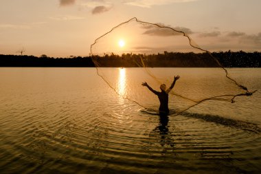 Balıkçı gün doğumunda ağ atıyor.