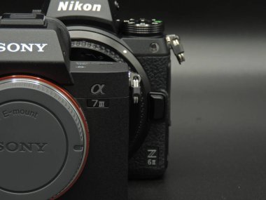 Nikon Z6 ii (sürüm 2) vs Sony Alpha 7 m3 (a7m3), kamera yüzleşme ve rekabet. Karanlık arka plan. Sony mi Nikon mu kazanacak? En iyi markalardan en iyi aynasız kameralar.