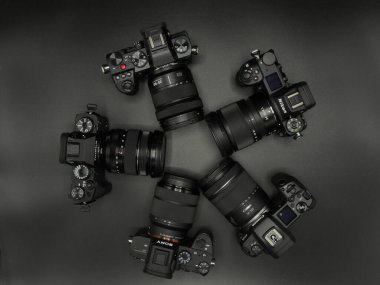 Nikon Z6, Fujifilm X-T4 and Panasonic Lumix S5, Sony Alpha 7 mark III and Canon R black top cameras from well-known manufacturers. Competition. Dark background. Macro. clipart