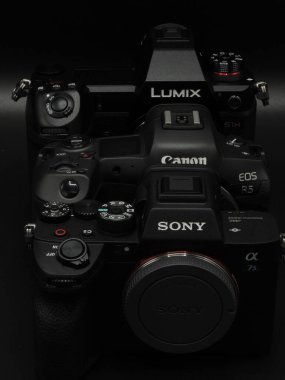Sony A7S mark3, Canon R5 and Lumix S1H are black top cameras from well-known manufacturers. Competition. Dark background. Macro. clipart