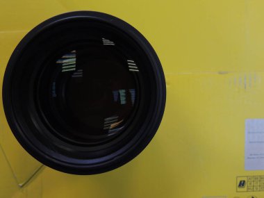 Genç bir adamın erkek elinde mercek yansıması olan kamera merceği. Karanlık arka plan. Kolunda bilezik var. Renkli gölgeler ve yansımalar. Makro. Cam ve yansıma.