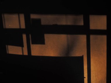 Arka planda gölgeler ve güneşten gelen ışık var. Karanlık arka plan. Masaüstü arkaplanı. Siyah, gri ve sarı. Venedik alçısı.