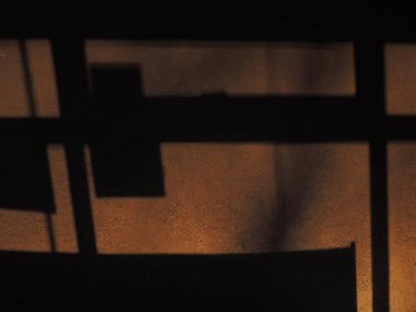 Arka planda gölgeler ve güneşten gelen ışık var. Karanlık arka plan. Masaüstü arkaplanı. Siyah, gri ve sarı. Venedik alçısı.