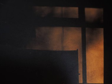 Arka planda gölgeler ve güneşten gelen ışık var. Karanlık arka plan. Masaüstü arkaplanı. Siyah, gri ve sarı. Venedik alçısı.