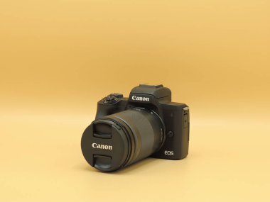 Sarı arka planda EF-M 18-150mm f3.5-6.3 lens ile Canon EOS M50 mark ii (M50m2). Blogcular için en iyi kameralardan biri..