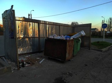 Garbage iron container in Russia. Iron fence made of metal. Garbage dump and summer.