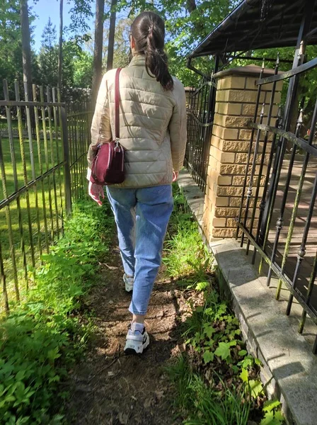 The girl walks along the path between the house and nature. Parks and cute houses in the city of Svetlogorsk.