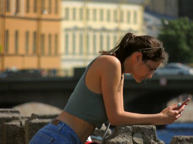 Kafkas görünümlü, elinde telefon olan bir kız. Sosyal ağlarda çekim yapmak ve zaman geçirmek.