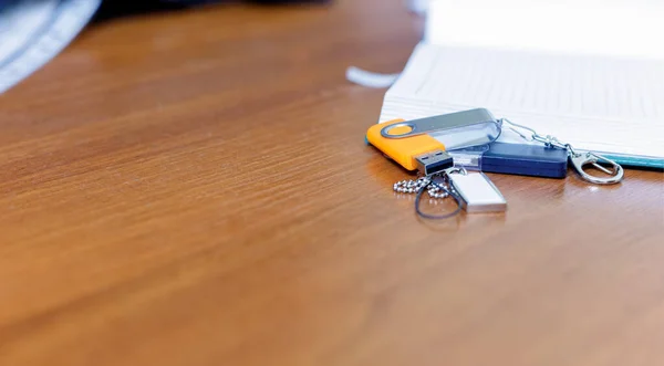 Empty open Notepad for writing lies on a wooden table with USB flash drives