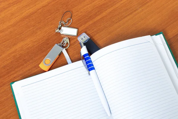 Empty open Notepad for writing lies on a wooden table with pan and USB flash drives