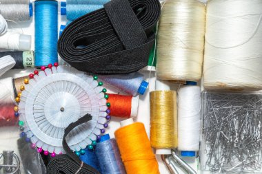 Beyaz arkaplanda renk iplikleri ve dikiş aksesuarları