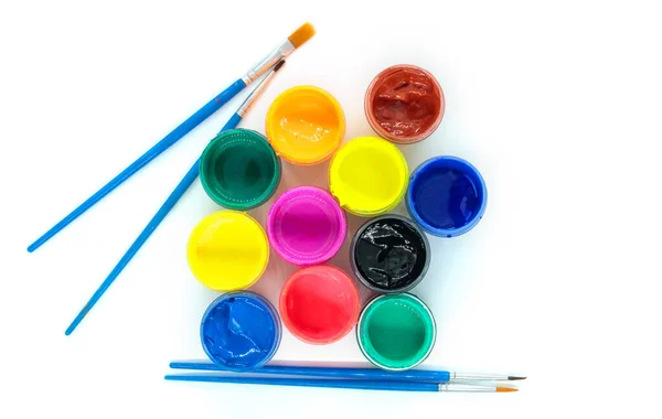 jars of colorful paint with open lids and brushes, top view close up, isolated object