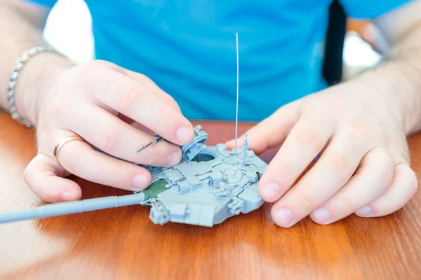 Bir adam plastik bir tank oyuncağı yapar, bir tank tareti monte eder.