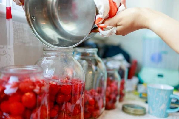 一个女人把热水倒入盛放草莓的玻璃瓶里 她就会做出甜菜 — 图库照片