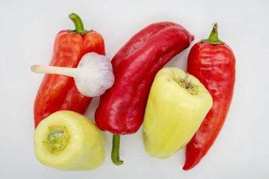 Üç kırmızı biber, iki yeşil ve sarımsak beyaz arka planda, yakın plan, izole