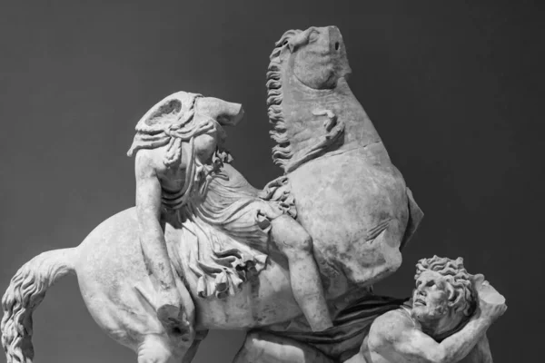遺跡の古典的な大理石の彫像の黒と白の写真は 男を攻撃する無頭の馬のライダーを示しています — ストック写真
