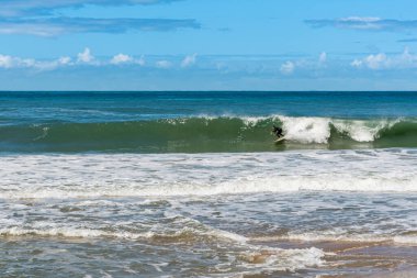 Brezilya sahilinin kıyısında dalgalar üzerinde duran sörfçü
