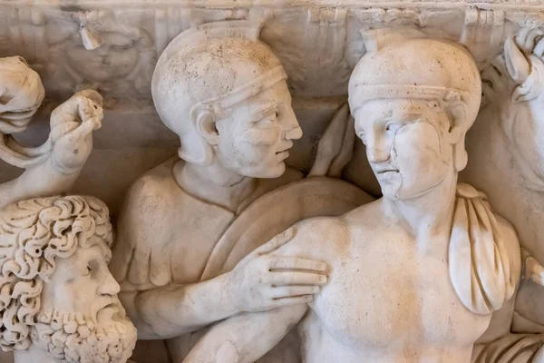 Close-up on faces of sculptures carved on marble representing two ancient roman soldiers interacting