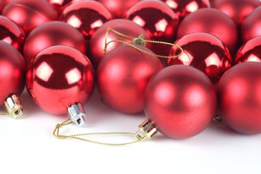 Beyaz zemin üzerinde kırmızı, parlak ve mat noel topları. Mesajınız için boş yer var.