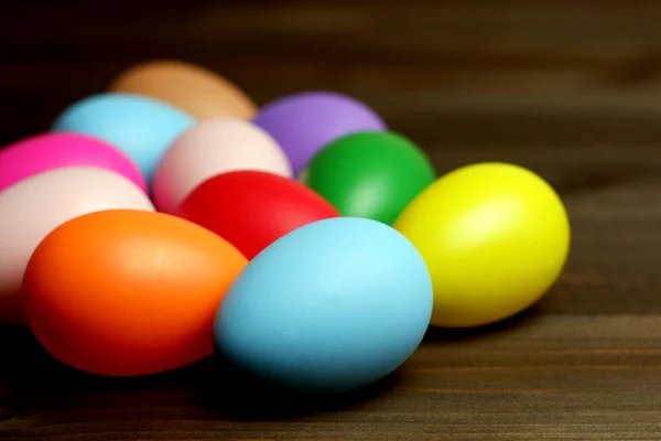 Multi colored easter eggs on dark wooden planks table close up view selective focus. Happy Easter concept. Easter holiday banner, card, poster, voucher, invitation templat