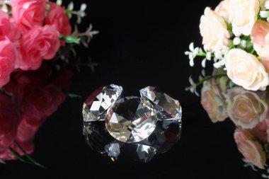 Üç mükemmel elmas ilk su ve pembe buketler ve çay gülleri siyah ayna arka planında yakın plan görüşlü. Mücevher satışı, davetiye, indirimli poster şablonu