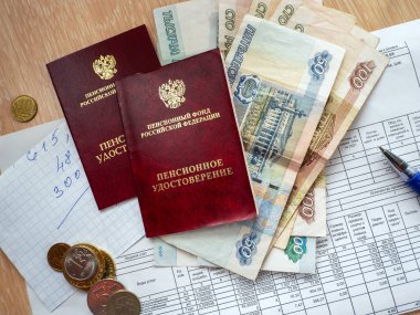 Rus parası, iki emekli maaşı sertifikası, bir kalem ve faturaların ödenmesi makbuzunun üstünde numaralar olan bir kağıt parçası. Rus belge ve rublesiyle arka plan.