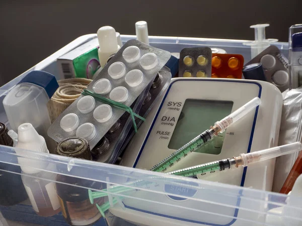 First aid kit with medicines. Tonometer, syringes, tablets and other medical devices are placed in a plastic box. Medical background with first aid kit.