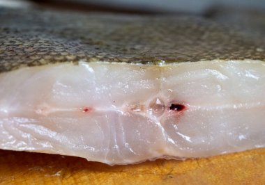 Büyük bir çiğ balık parçası ahşap bir tahtanın üzerinde yatıyor. Yemek pişirmek. Yakın plan..