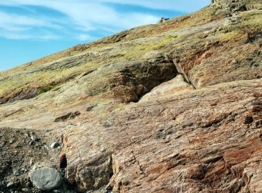 Çatlakları ve çukurları olan sert kayalık bir yamaç. Yakın plan. Doğal taş arkaplan.