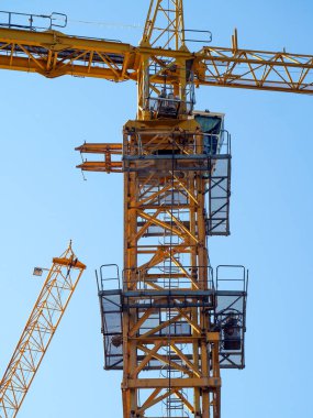 Platformları, kulübesi ve mavi gökyüzüne karşı patlamanın bir parçası olan bir vinç kulesinin metal yapısının üst kısmı. Arkasında başka bir vinç patlaması görünüyor. Sanayi geçmişi.