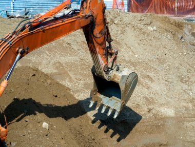 Kazı kovası, toprağı almak için çukura indiriliyor. Yakın plan. İş ve endüstri için inşaat alanına sahip bir arka plan.