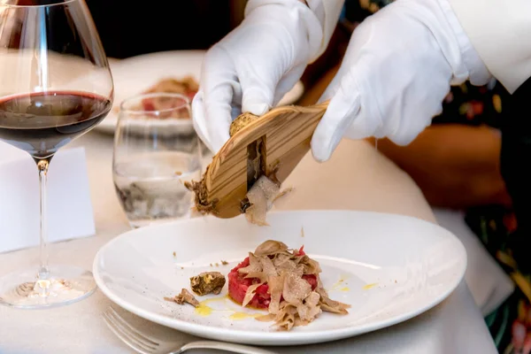 Alba white truffle sliced by the waiter's white gloved hands. Raw ground beef