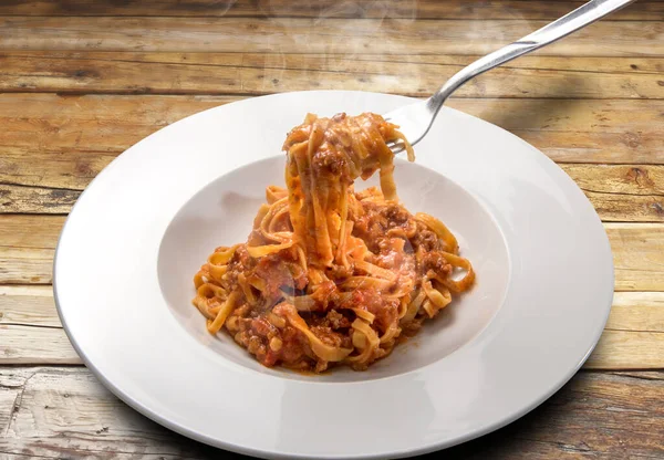 意大利面鸡蛋 意大利塔利亚泰勒 配以肉和番茄酱 放在烤好的盘子里 放在生硬的木制底座上 — 图库照片